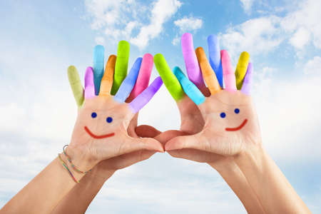 Painted hands with smile on sky background