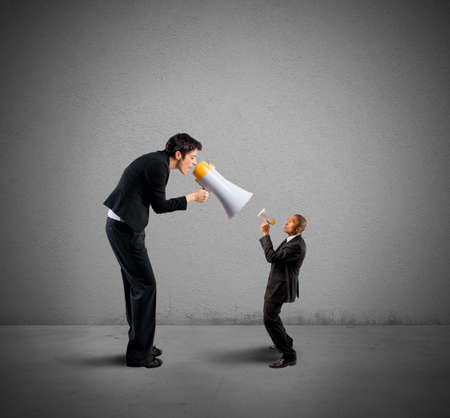 Businesswoman shouting a businessman through a megaphoneの写真素材
