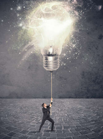 Concept of illuminate an idea with a businessman and big lightbulbの写真素材