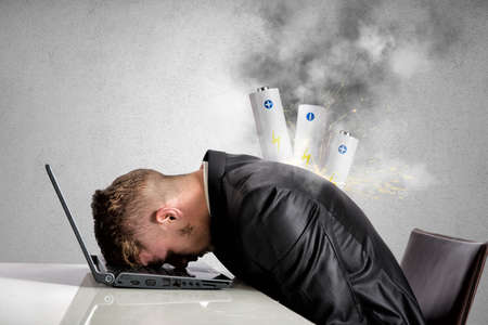 Stressed businessman with explosion of discharged batteryの写真素材