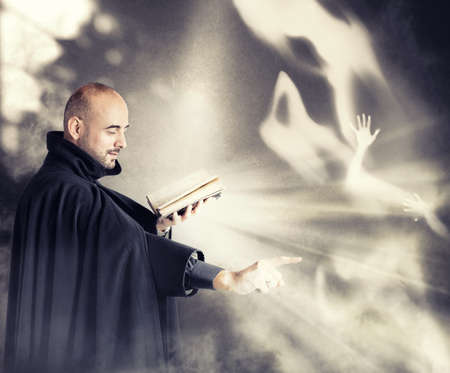 Exorcist priest fights a demon in a dark roomの写真素材