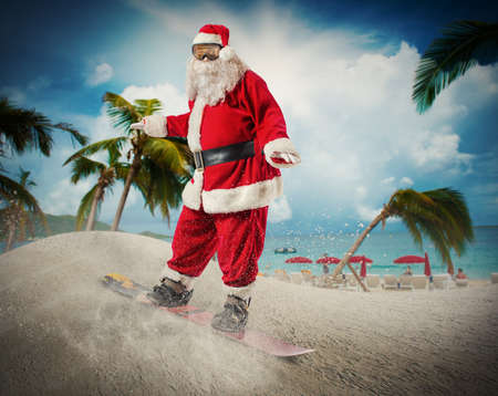 Funny santa claus goes fast on a snowboard in a tropical beachの写真素材
