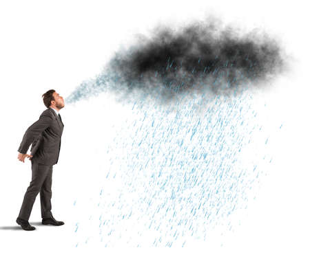 Businessman blowing away a black cloud with rainの写真素材
