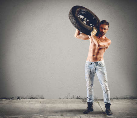 Seductive car mechanic working on a tireの写真素材