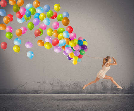 Carefree and happy girl jumping with balloonsの写真素材