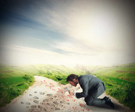 Businessman careful investigates such footsteps to followの写真素材
