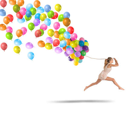 Carefree and happy girl jumping with balloonsの写真素材