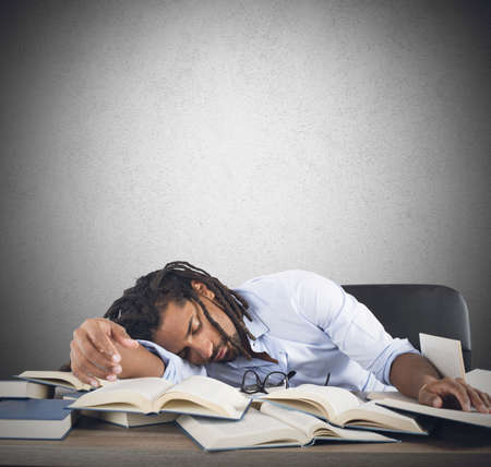 Tired teacher falls asleep while reading booksの写真素材