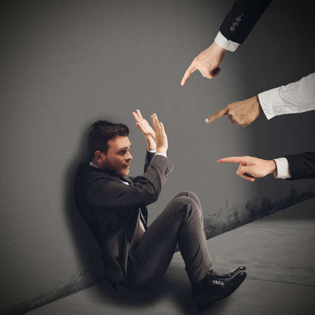 Businessman blamed unfairly by his work colleaguesの写真素材