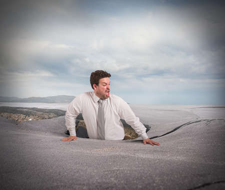 Businessman alone and afraid swallowed by asphaltの写真素材