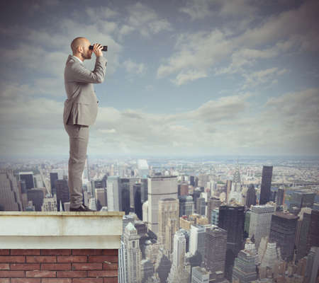 Curious businessman looks beyond with his binocularsの写真素材