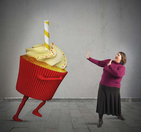 Fat woman is frightened by giant cupcakeの写真素材