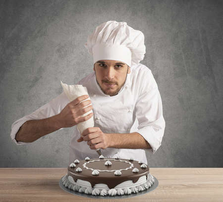 Pastry cook prepares a chocolate and cream cakeの写真素材