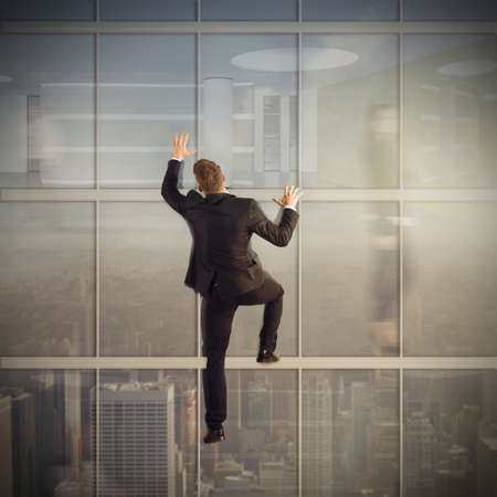 Businessman climb the glass of a skyscraperの写真素材