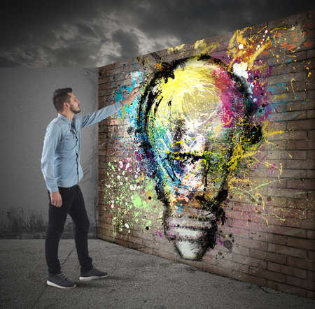 Boy draws a colored bulb on a wall