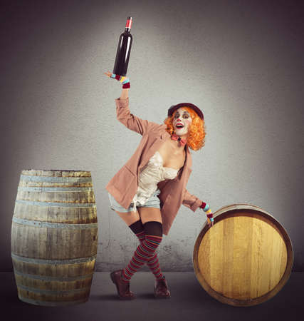 Drunk clown between wine bottles and barrelsの写真素材