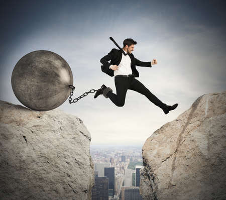 Businessman jumping with ball tied to footの写真素材