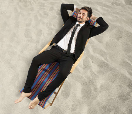 Businessman relaxes lying on a beach chairの写真素材