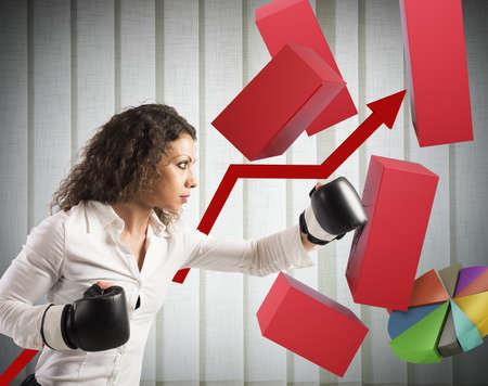 Businesswoman gives a punch to economic graphの写真素材