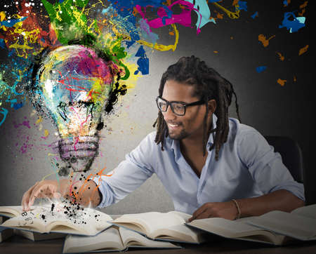 Man reads books with above colored bulbの写真素材