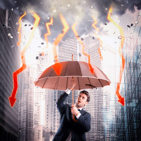 Businessman sheltered with umbrella from lightning arrowの写真素材