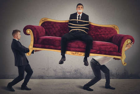 Employees raise and carry a trapped businessmanの写真素材
