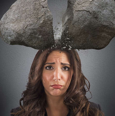 Businesswoman with split boulder above her headの写真素材