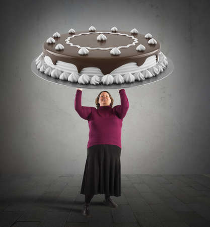 Fat woman holding a big chocolate cakeの写真素材