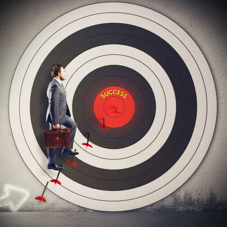 Man climbs on the arrow of targetの写真素材