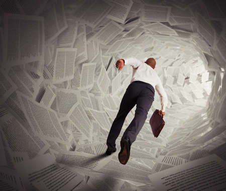Businessman runs through a tunnel of paperの写真素材