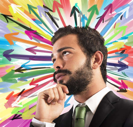 Businessman thinks with background of colored arrowsの写真素材
