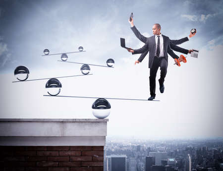Businessman balancing on boards with iron ballsの写真素材