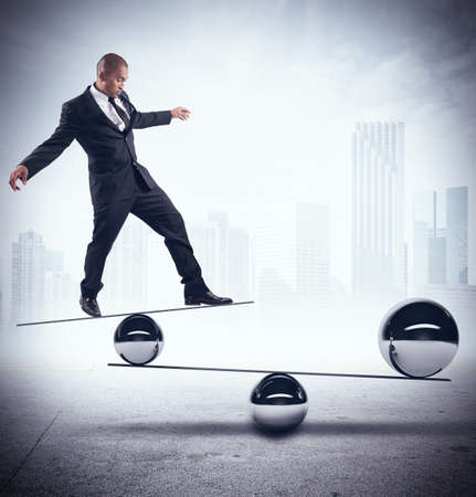 Businessman balancing on boards with iron ballsの写真素材