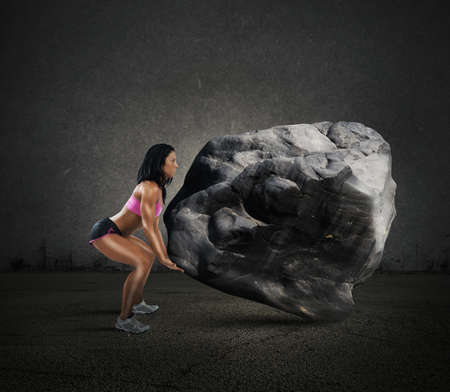 Muscular woman lifts a big boulder heavyの写真素材