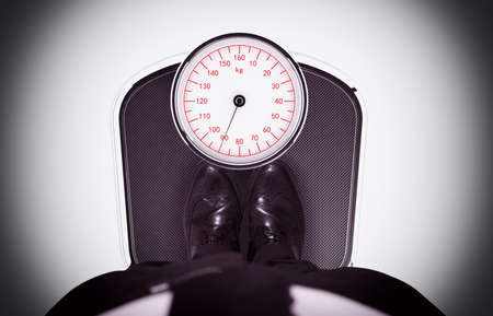 Man measuring his weight on the scaleの写真素材