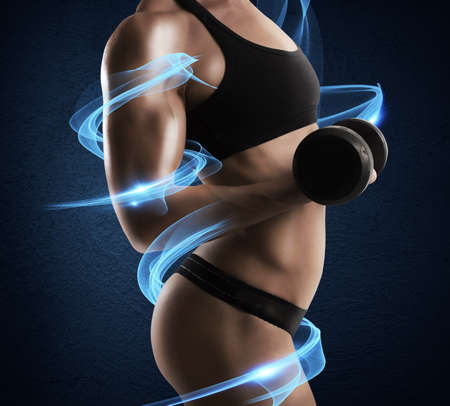 Muscular woman trains with light that surroundsの写真素材