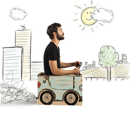 Boy driving cardboard car in drawing cityの写真素材