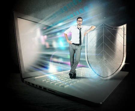 Small confident businessman with computer and shieldの写真素材