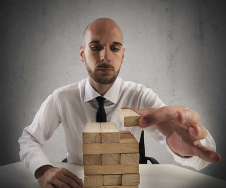 Businessman builds a tower with toy piecesの写真素材