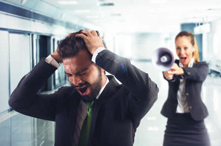 Boss scolds with megaphone a desperate employeeの写真素材