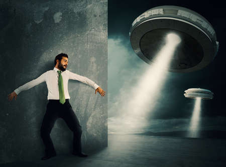 Man hides frightened by UFO space shuttleの写真素材
