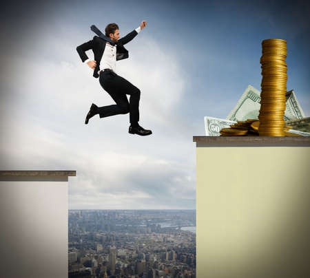 Determined businessman jumps risky to get moneyの写真素材