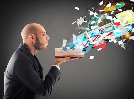 Businessman blowing over a magic business bookの写真素材