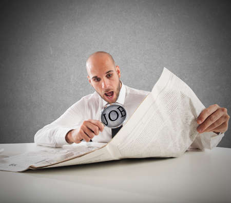 Businessman reading the newspaper with magnifying lensの写真素材