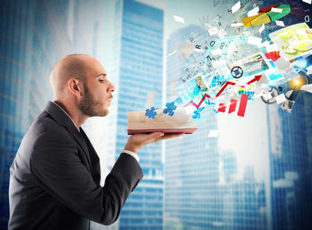 Businessman blowing over a magic business bookの写真素材