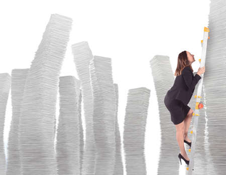 Businesswoman climbs on scale of sheets pilesの写真素材