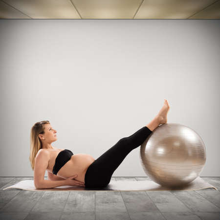 Pregnant woman does fitness exercises with ballの写真素材