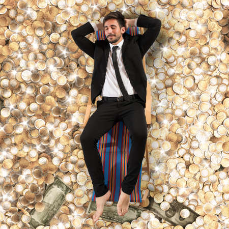 Carefree businessman on deck on the moneyの写真素材