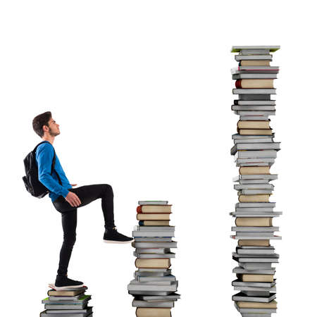 Boy with backpack climbs a books scaleの写真素材