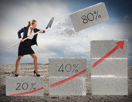 Businesswoman pulls big bricks with a shovelの写真素材